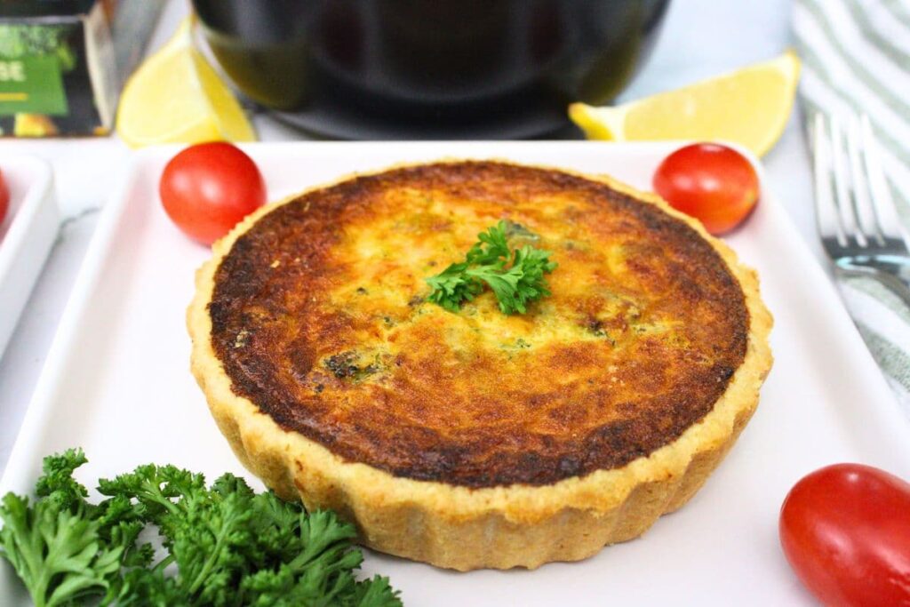uncut trader joes broccoli cheddar quiche cooked in the air fryer on a square plate
