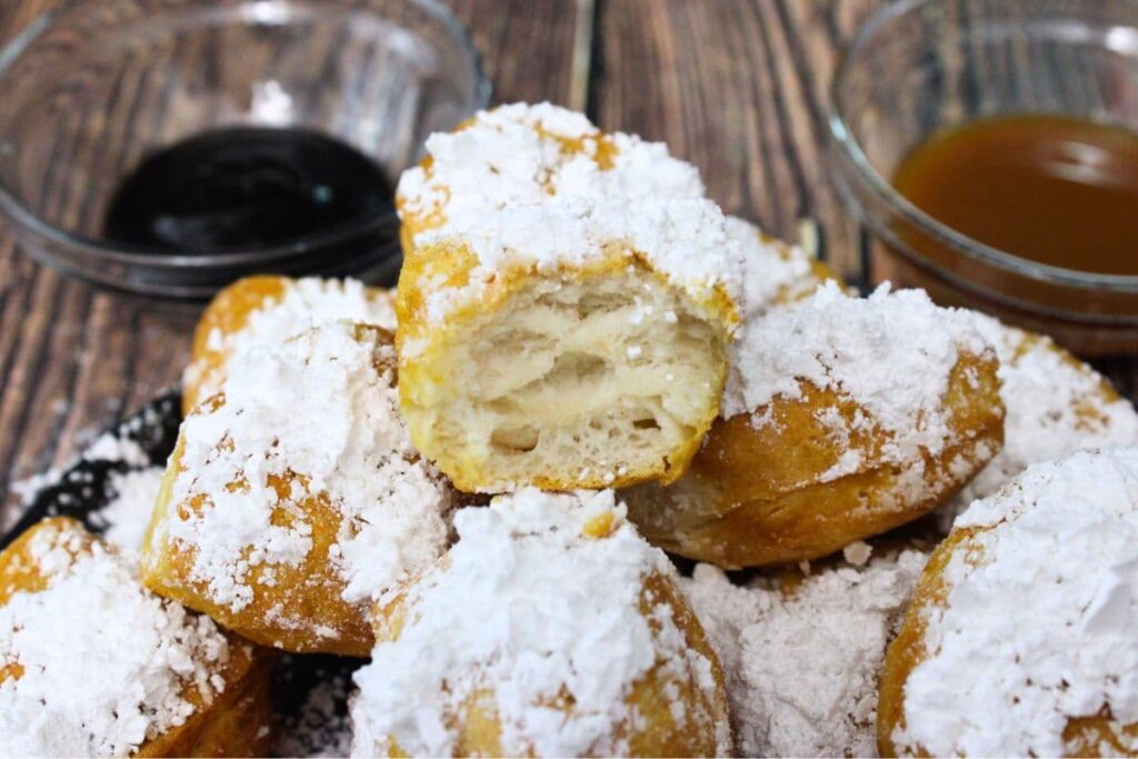 air fryer beignets with biscuits stacked on a plate and cut open to show the inside