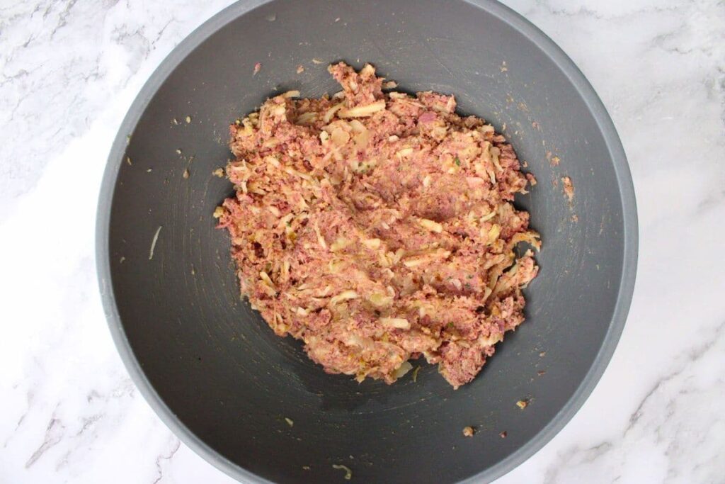 combine corned beef, shredded swiss cheese, rye breadcrumbs, sauerkraut, eggs, and seasoning in a mixing bowl