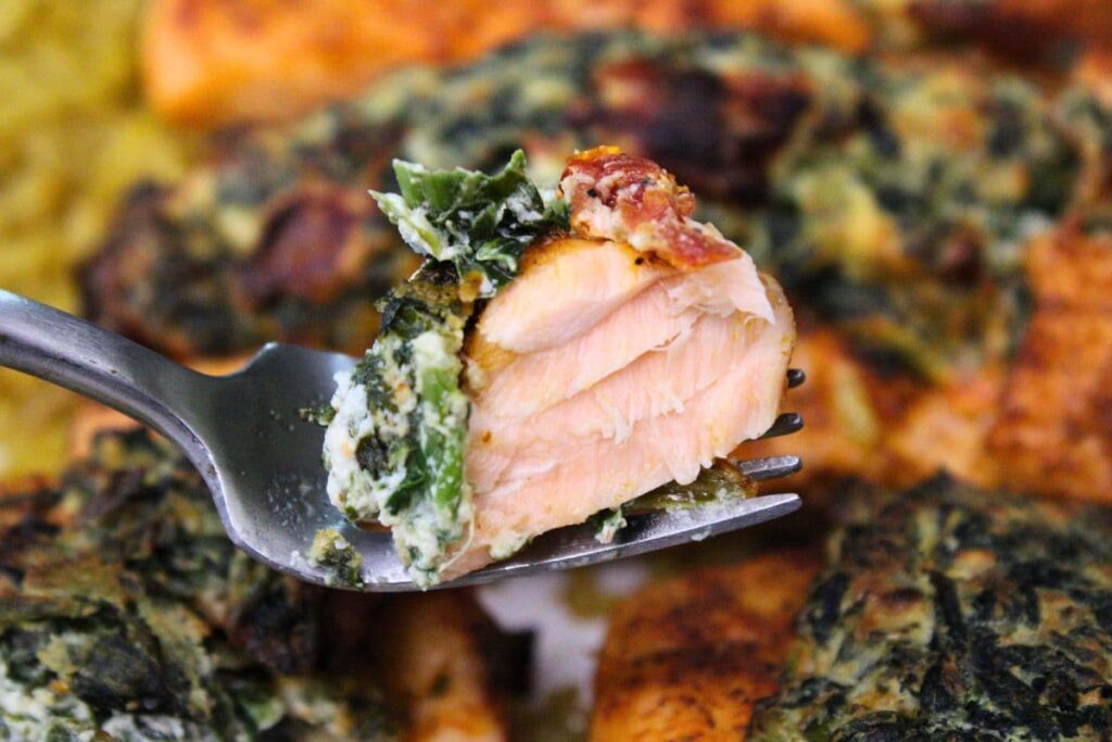 holding up a fork with a piece of air fryer spinach stuffed salmon on it