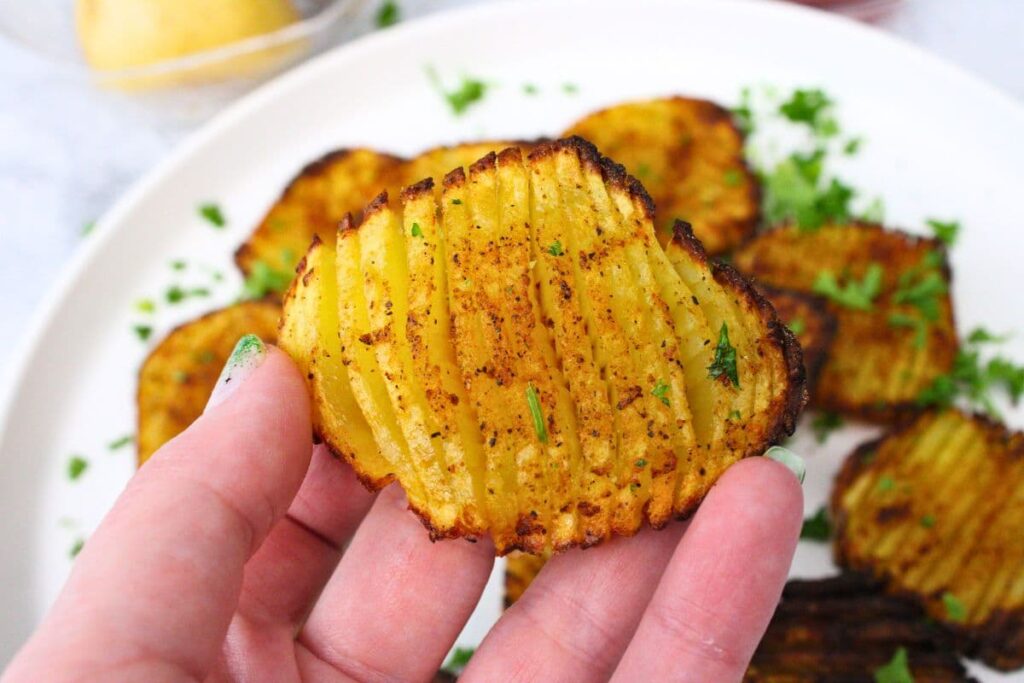 holding up a golden brown air fryer accordion potato
