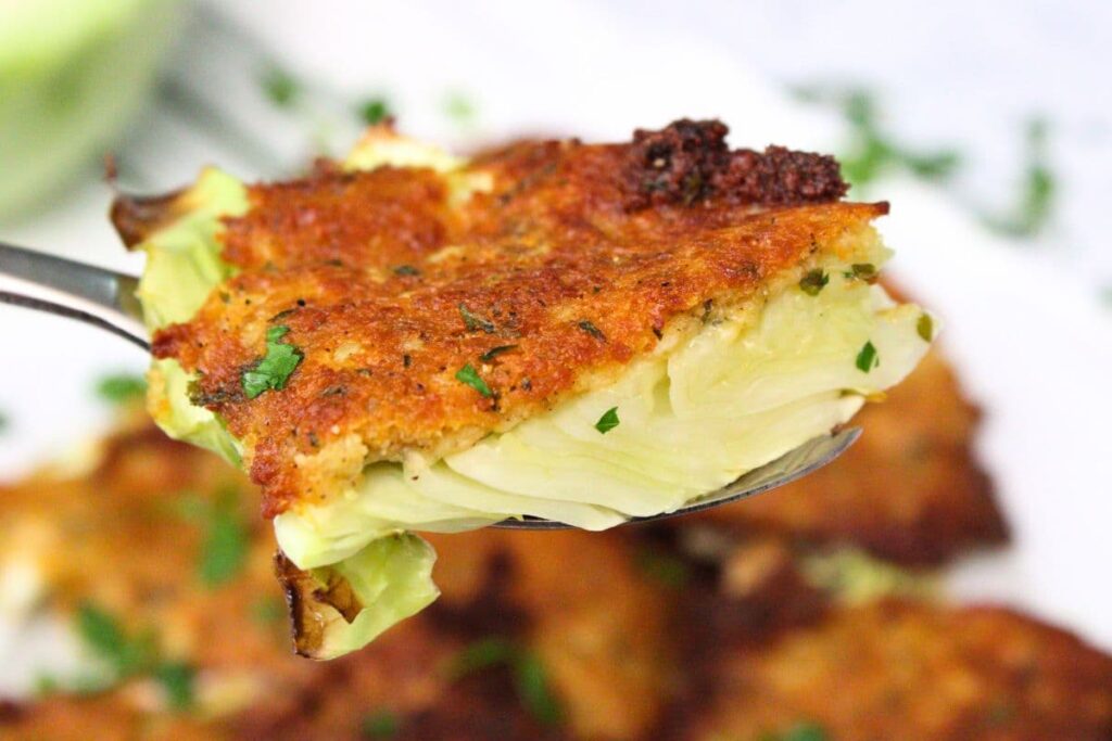 holding up a slice of parmesan crusted cabbage cooked in the air fryer on a fork