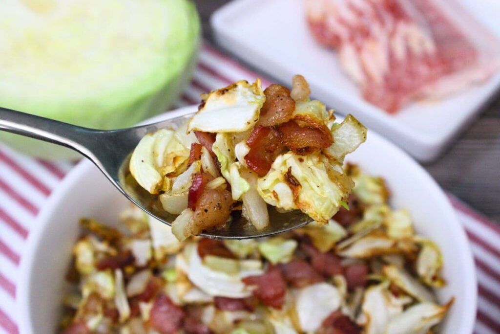 holding up a spoonful of southern air fryer cabbage and bacon