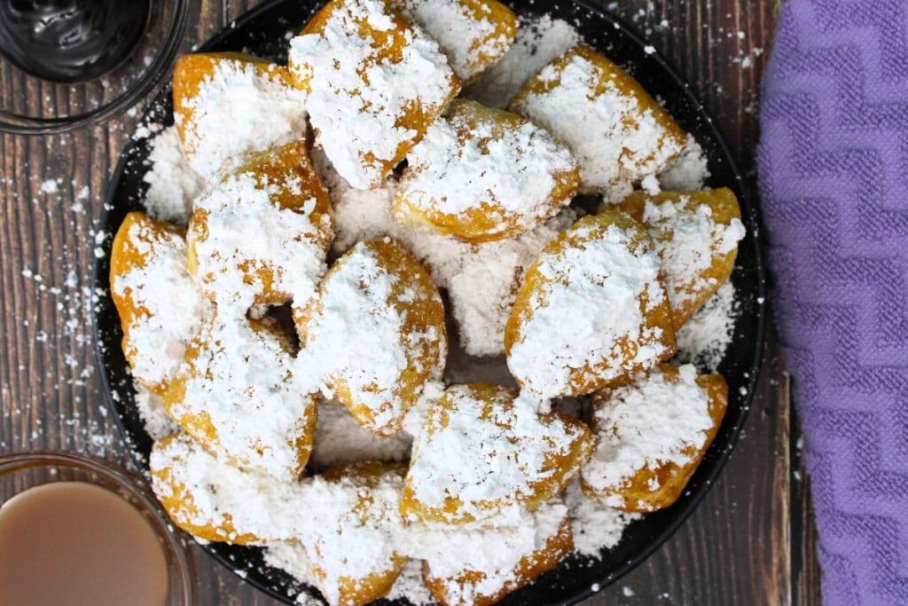 overhead view of air fryer beignets from biscuits covered in powder sugar