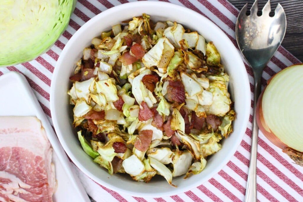 overhead view of air fryer cabbage and bacon in a bowl with a serving spoon