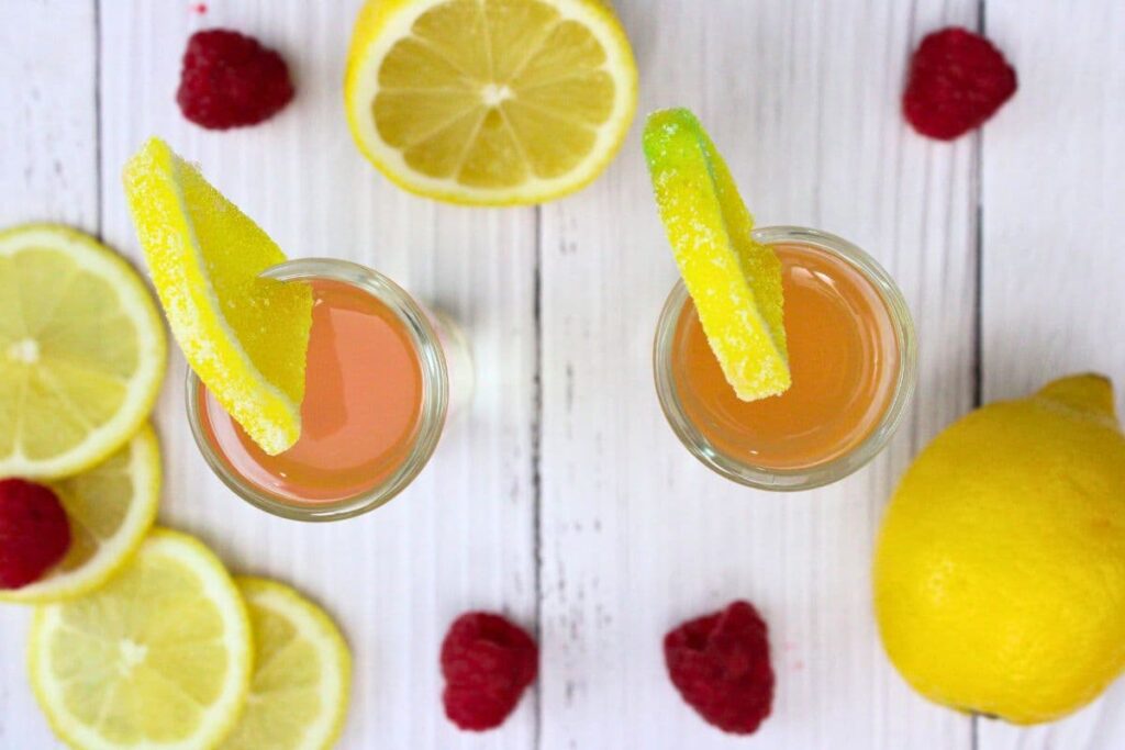 overhead view of layered pink whitney shots with candy lemon wedges