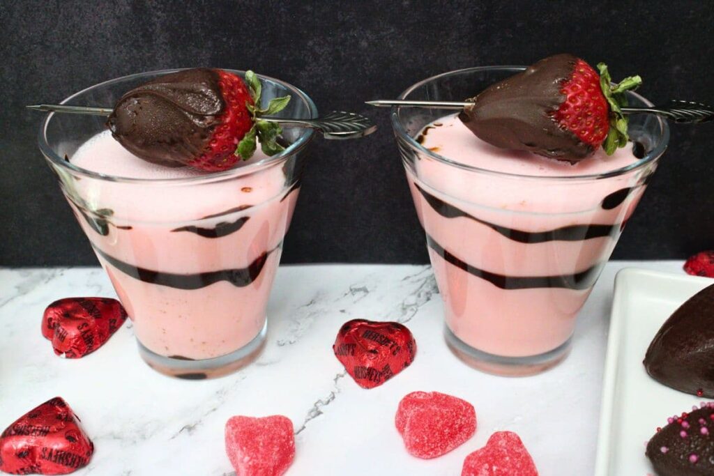 two chocolate covered strawberry martinis surrounded by candy hearts