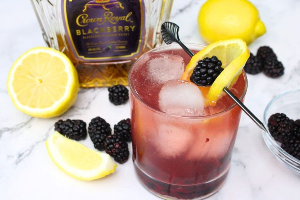 blackberry whiskey fizz in front of a bottle of crown royal blackberry