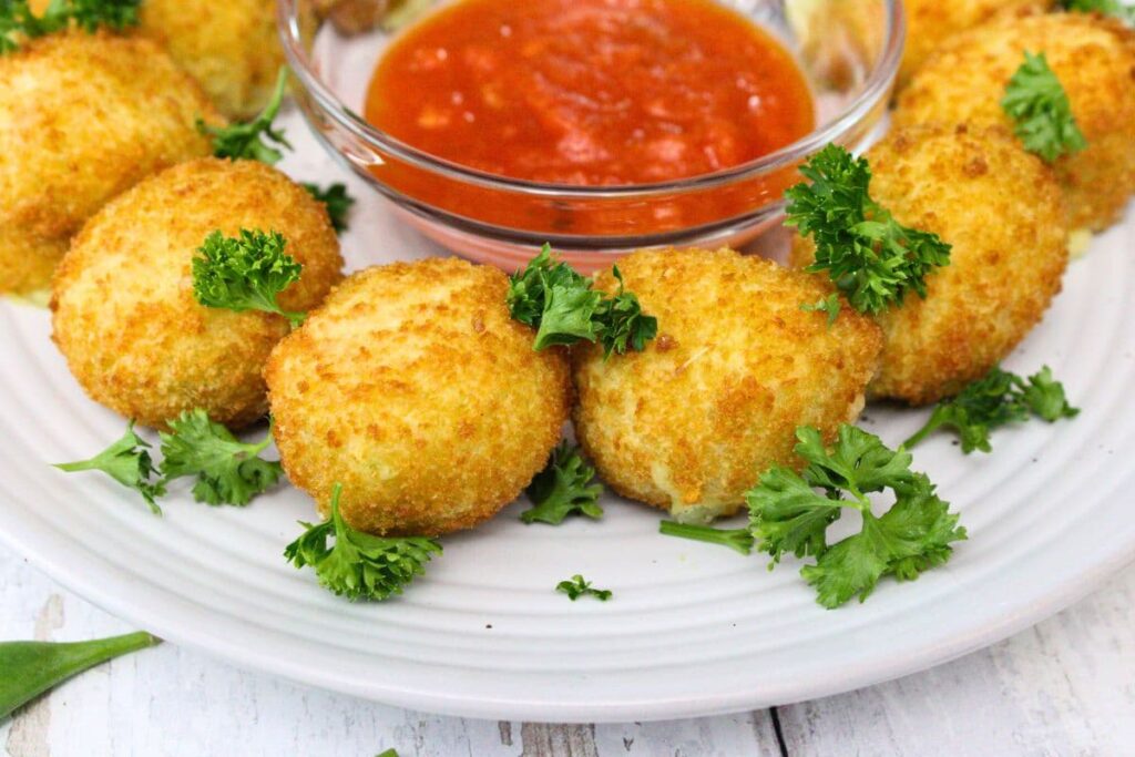 closeup view of air fryer frozen arancini on a plate with marinara and parsley