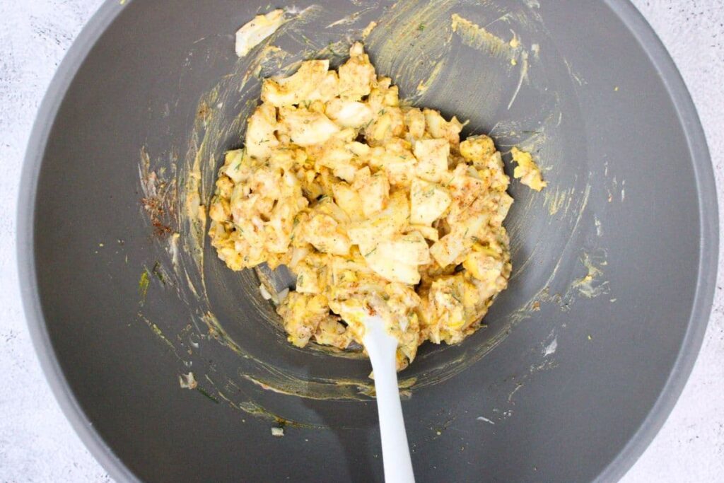 combine chopped eggs with mayonnaise, mustard, and seasonings