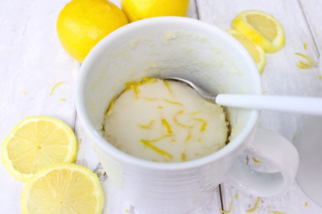 dipping a spoon into a cup filled with lemon mug cake