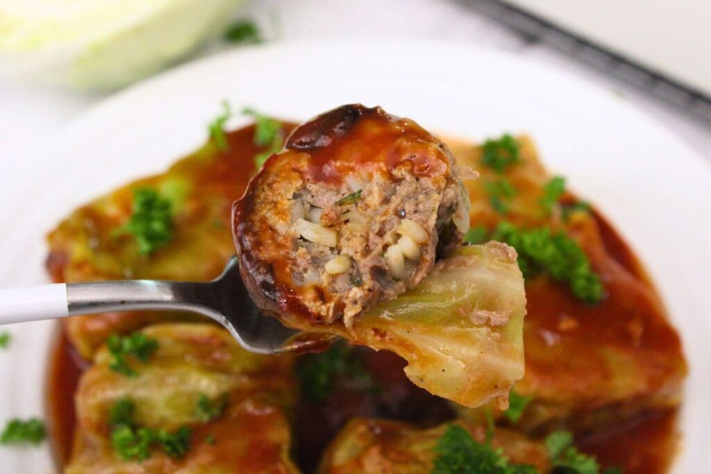 hold up a fork with a slice of air fryer stuffed cabbage roll