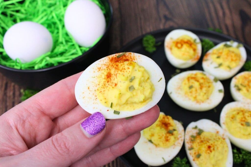 holding up a deviled egg cooked in the air fryer