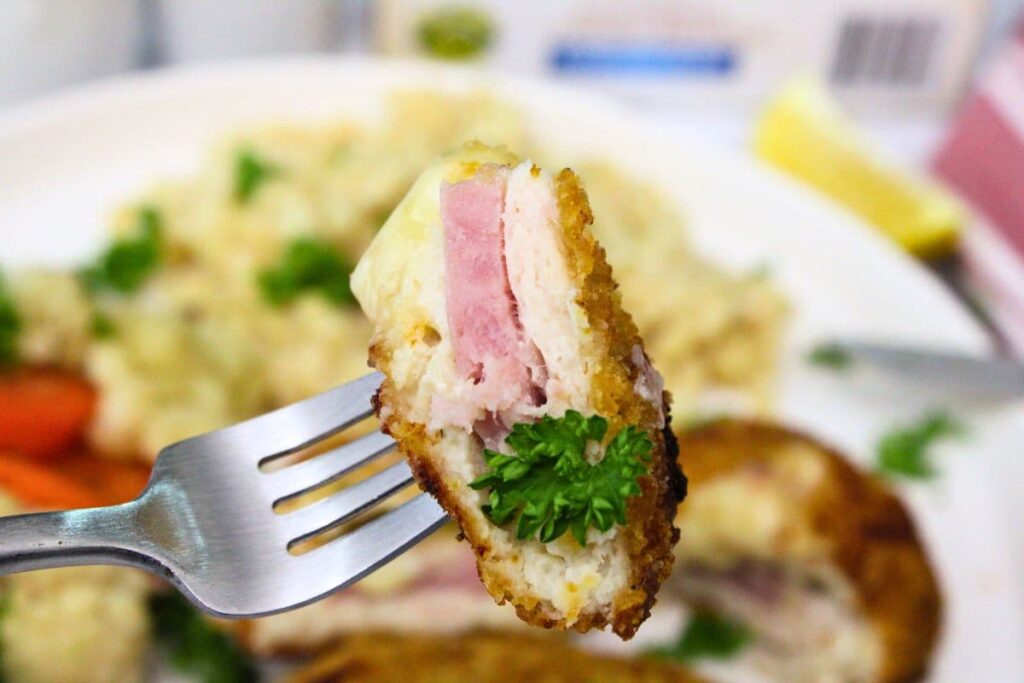 holding up a fork with a piece of air fried chicken cordon bleu