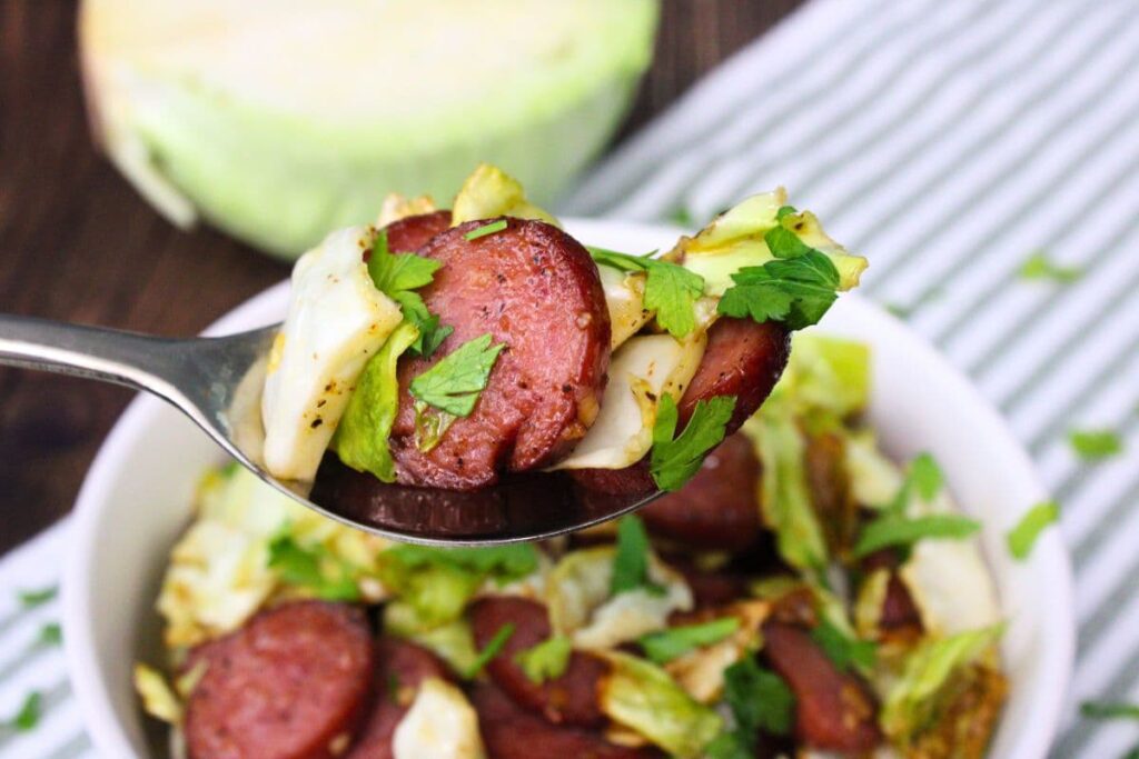 holding up a spoonful of air fryer cabbage and sausage