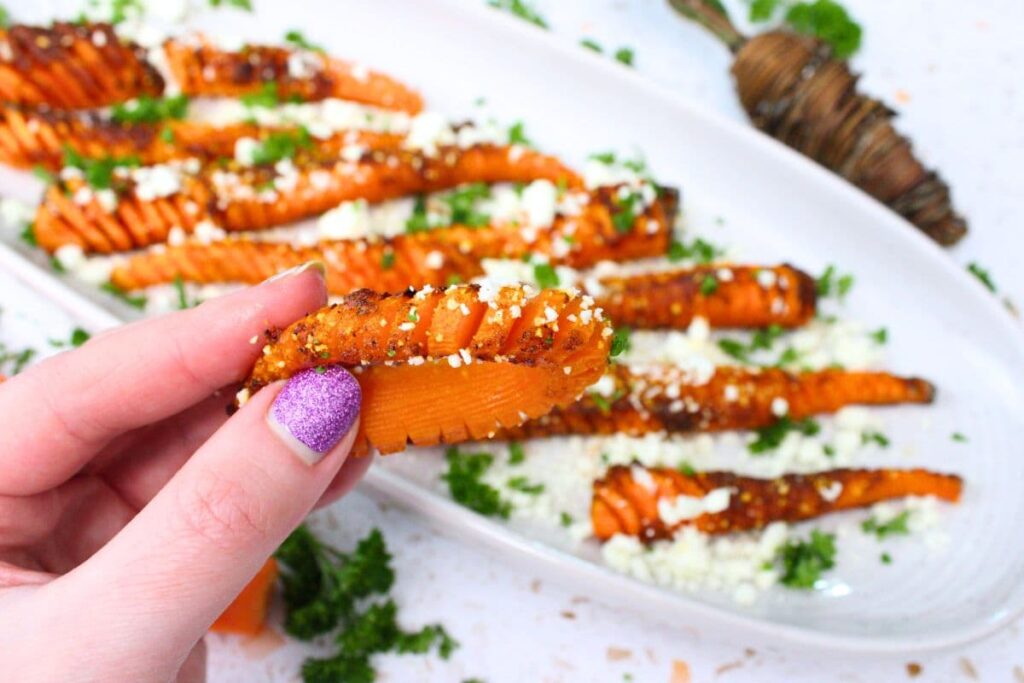 holding up an air fryer hasselback carrot bent around to show off the slices