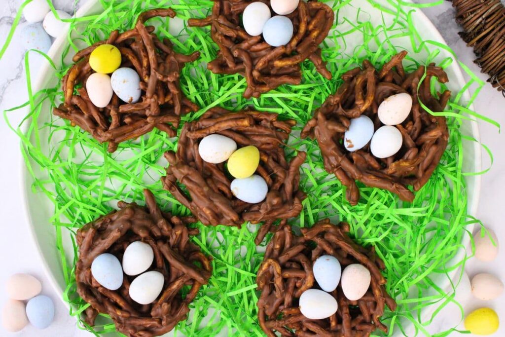 overhead view of Easter birds nest treats with candy eggs on a plate with fake grass