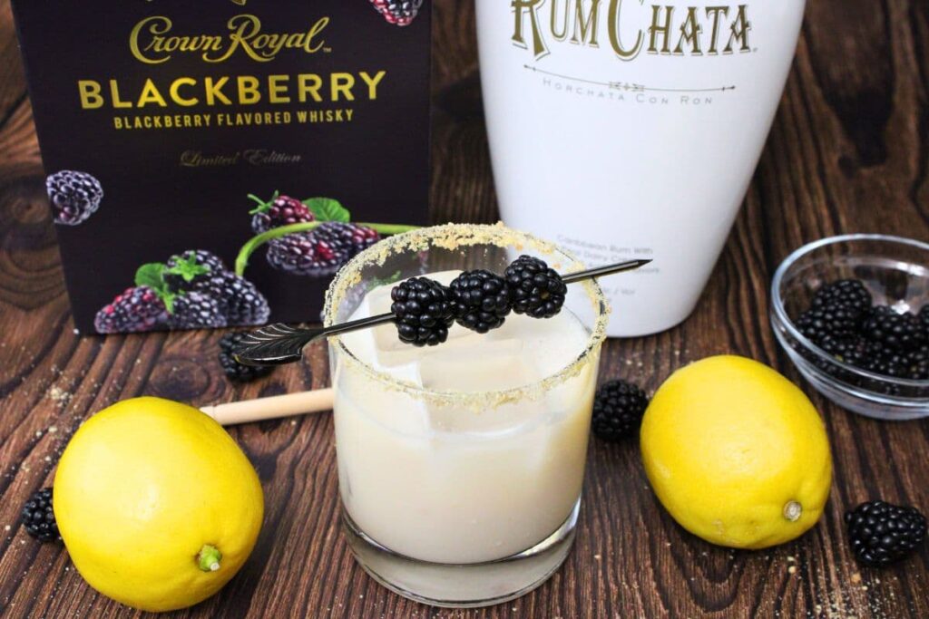 single crown royal blackberry cobbler cocktail in front of blackberry whiskey and rumchata bottles