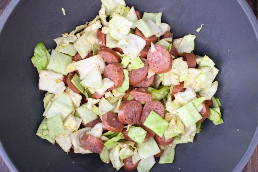 toss sausage and cabbage with olive oil, garlic, and cajun seasoning