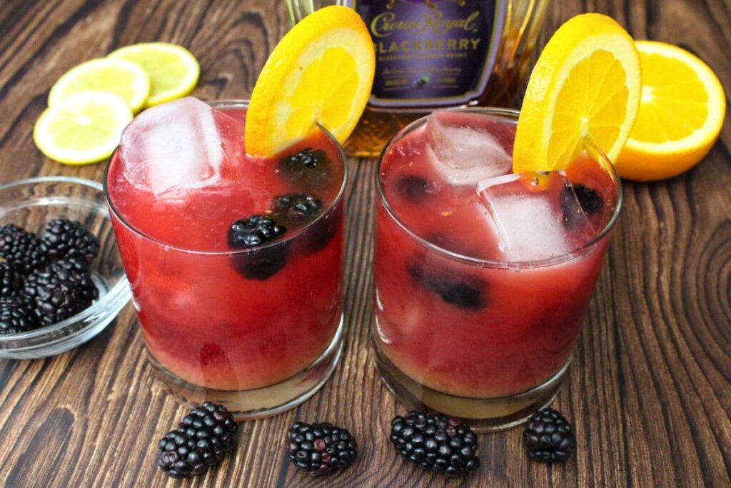 two blackberry rambler cocktails in front of the crown royal bottle