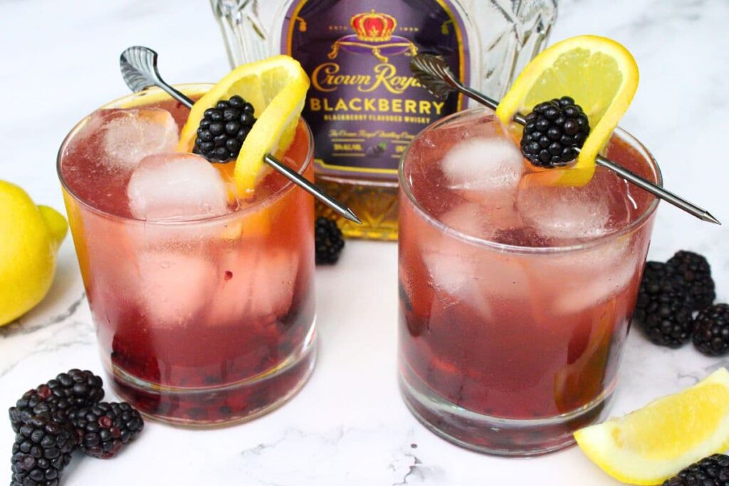 two crown royal blackberry whiskey fizz drinks in front of the bottle