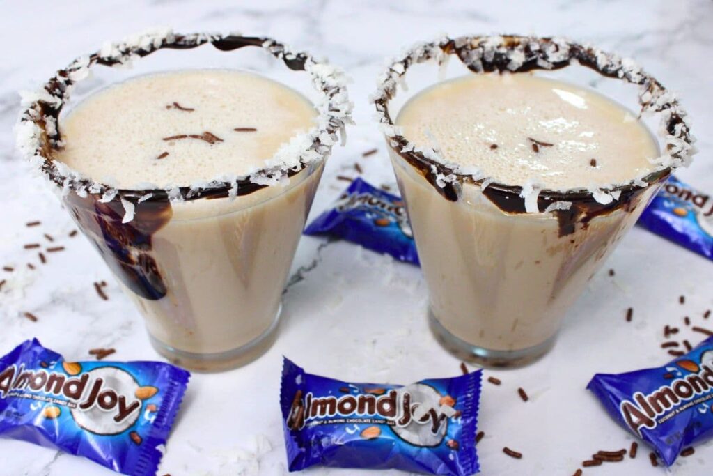 two glasses filled with almond joy martini surrounded by candy bars
