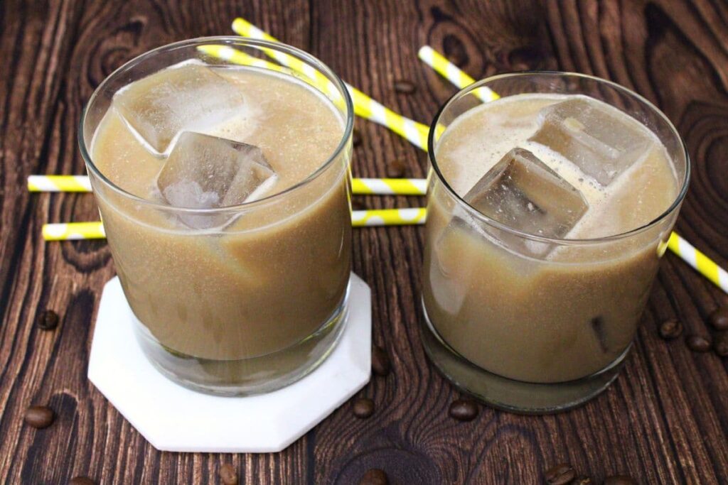 two long island iced coffee cocktails in whiskey glasses on wooden top