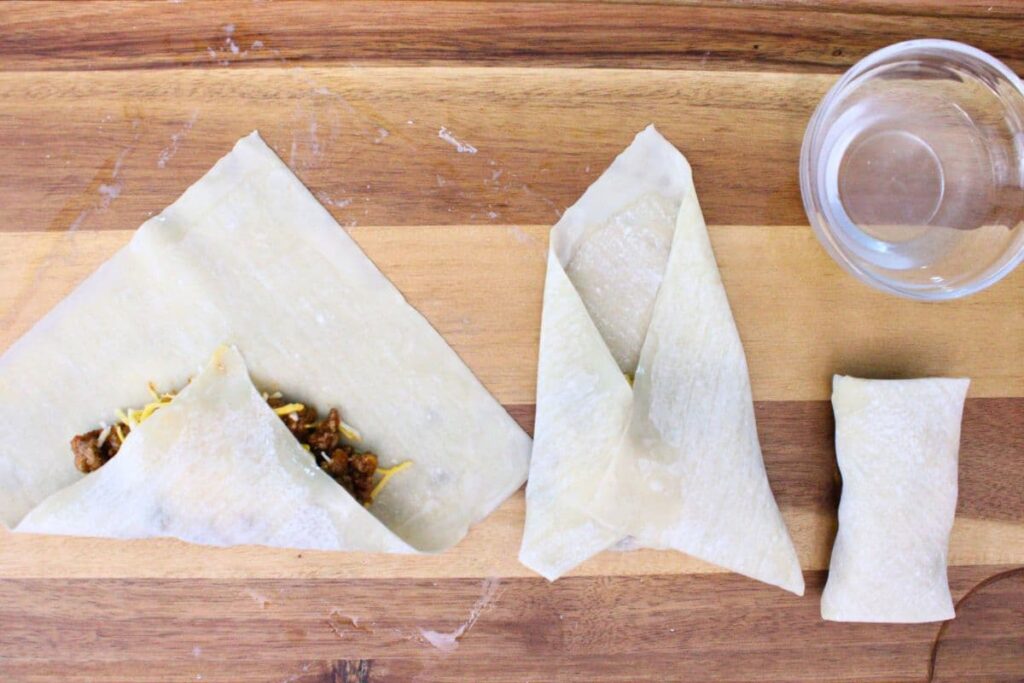 carefully roll up the egg roll wrapper over the beef and cheese filling