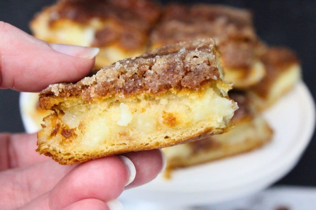 holding up a sopapilla cheesecake bar cooked in the air fryer