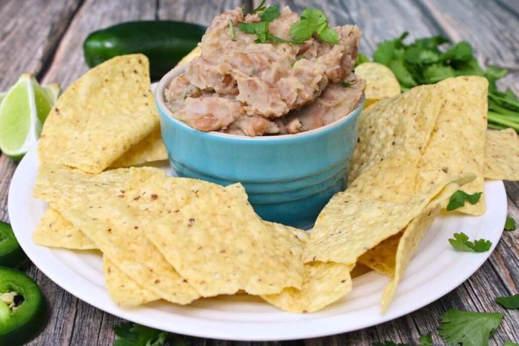 microwave refried beans in a ramekin surrounded by tortilla chips