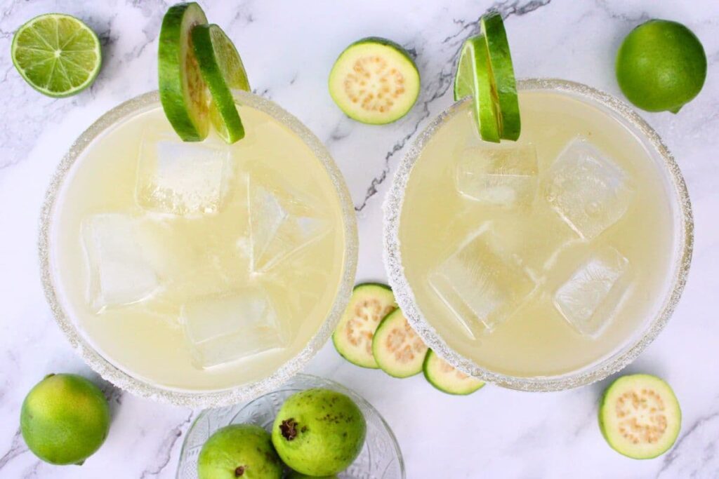 overhead view of two guava margaritas with lime and guava in the rim