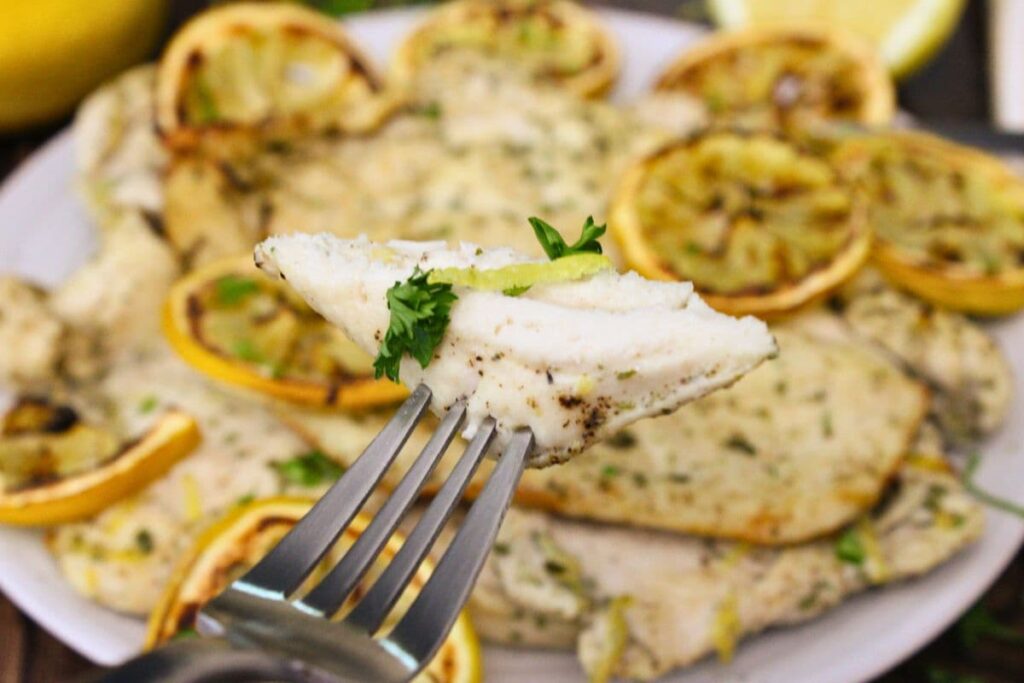 holding up a piece of air fryer lemon chicken on a fork