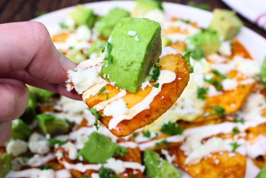 holding up an air fryer chilaquiles with a chunk of avocado