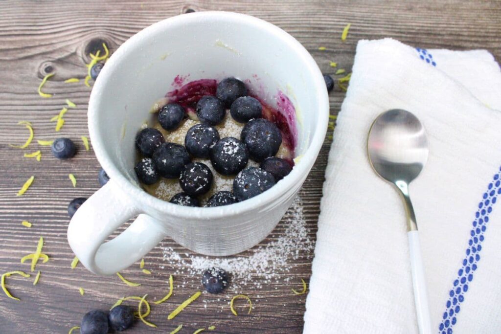 lemon blueberry mug cake next to a spoon