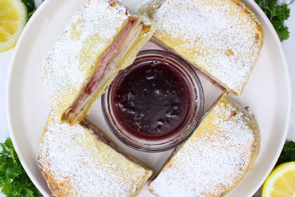 overhead view of two air fryer monte cristo sandwiches cut in half circling a bowl of raspberry jam
