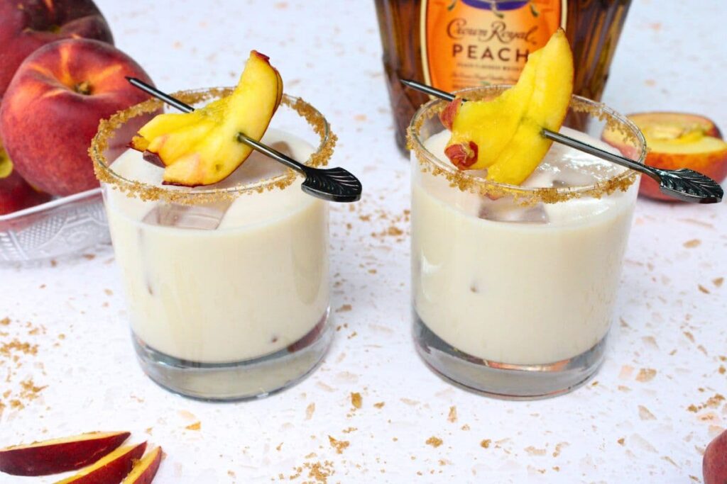 two peach cobbler cocktails in front of crown royal bottle