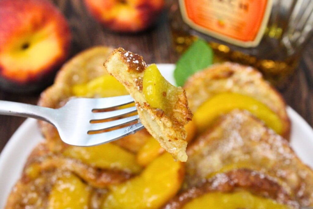 air fryer crown peach whiskey french toast being held up on a fork