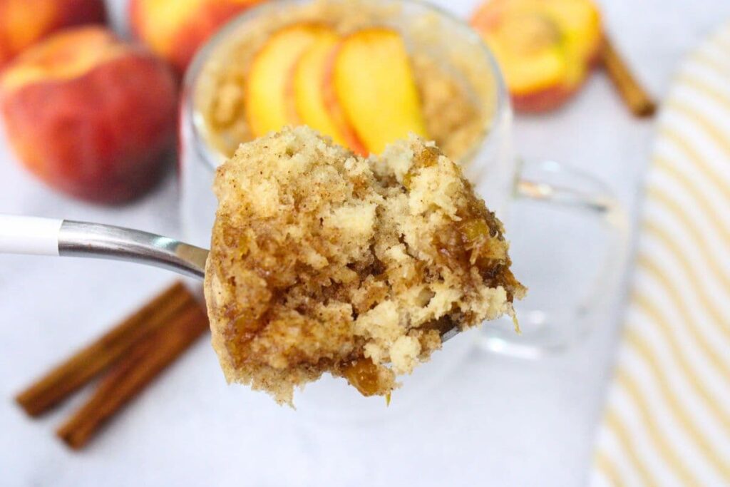 holding up a spoonful of microwave peach mug cake