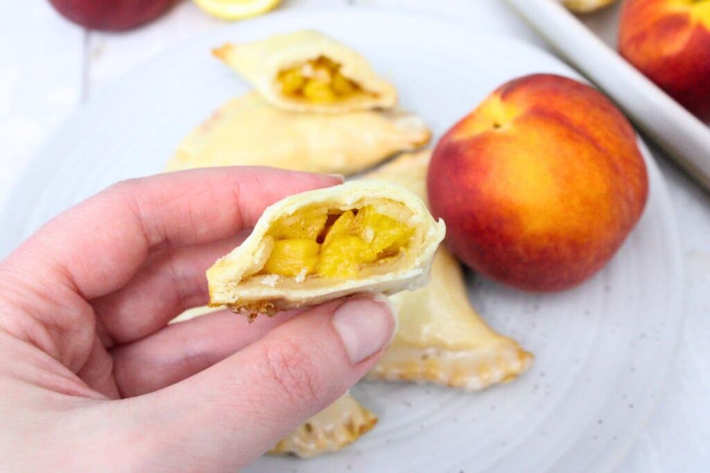 holding up half of an air fryer peach hand pie