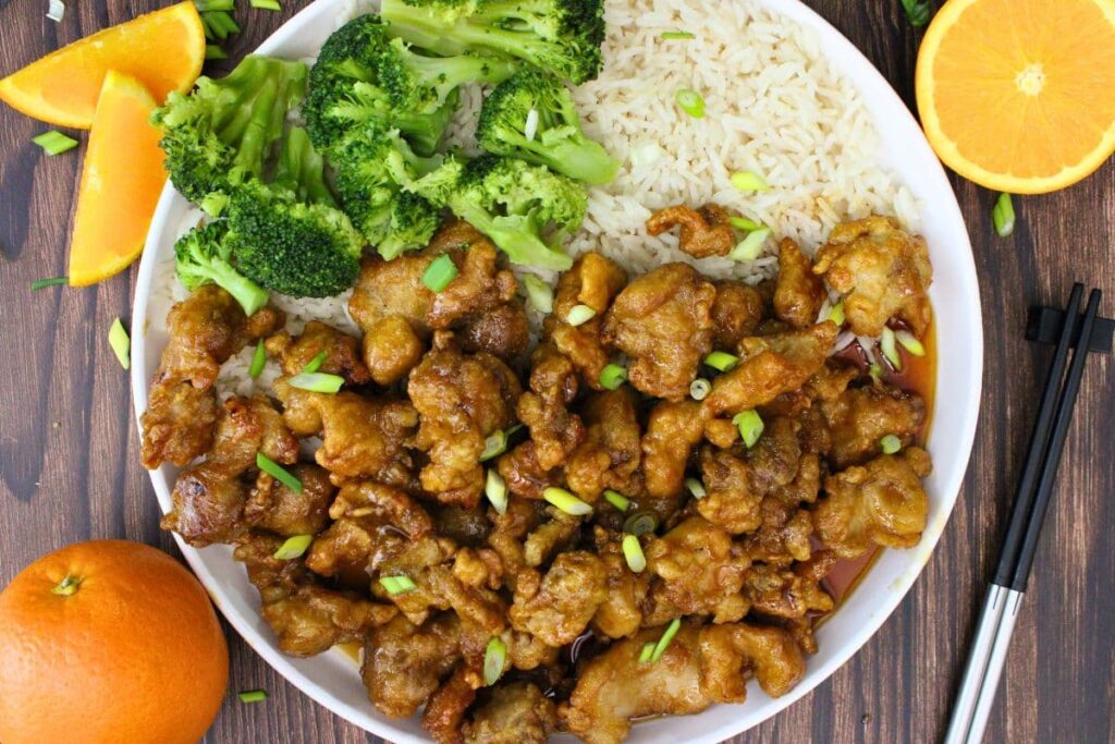 overhead view of air fryer trader joes orange chicken on a plate with white rice and steamed broccoli