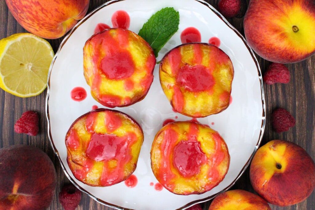 overhead view of four halves of air fryer grilled peaches drizzled in raspberry melba sauce