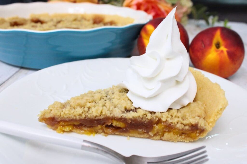 slice of microwave peach pie on a plate with a swirl of whipped cream