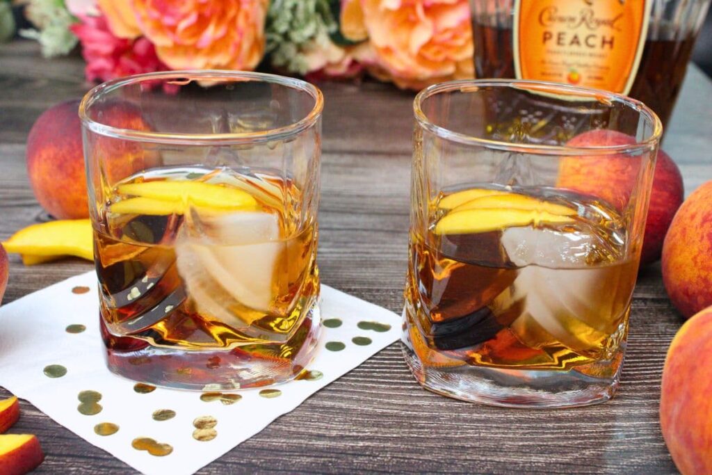 two crown peach old fashioned drinks on a wooden table