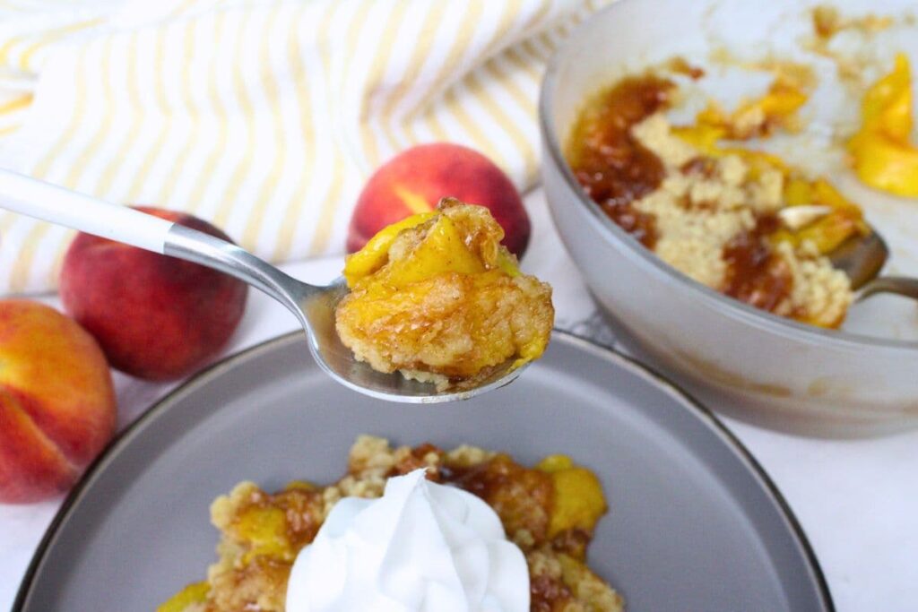 holding up a spoonful of peach crumble made in the microwave