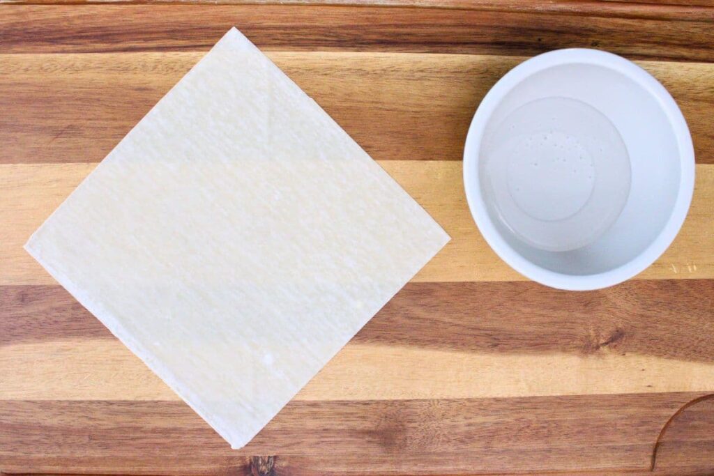 lay egg roll wrapper with a small bowl of water