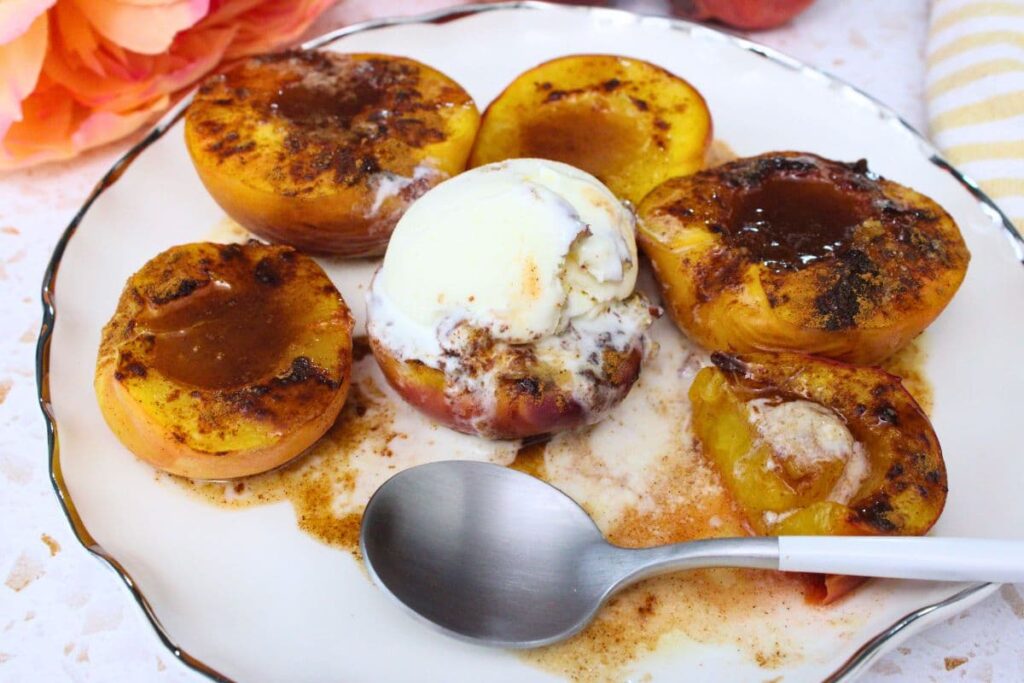 microwave fresh baked peaches on a plate cut into with a spoon and ice cream