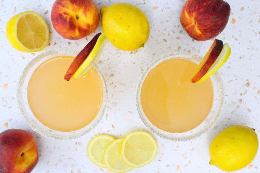 overhead view of two peach lemon drop martini drinks surrounded by fresh fruit