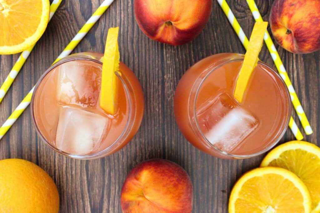 overhead view of two texas roadhouse peach fuzz drinks on a wooden table