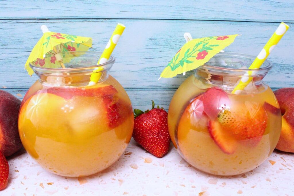 two tropical crown royal peach punch drinks against a blue wooden background