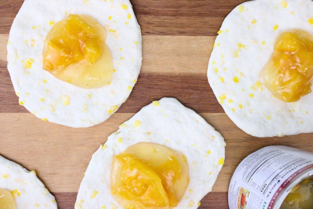 add peach pie filling into the center of each biscuit